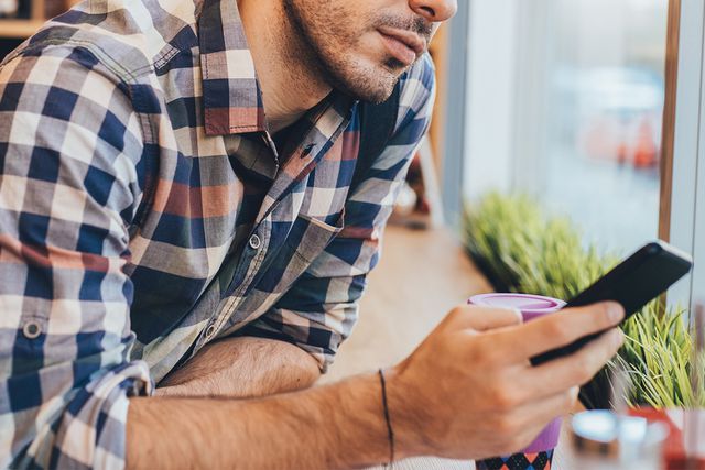 Man using cell phone - stock photo Getty Man looking at his phone (stock image)