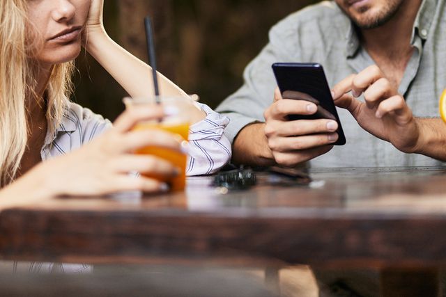 Young man using cell phone in an outdoor cafe while his girlfriend is feeling bored. Getty Upset woman and man on phone (stock image)