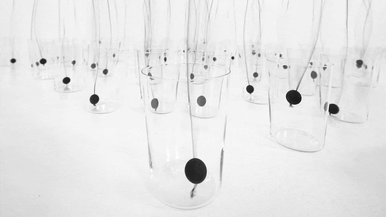 black balls spin in glass cups on a white floor